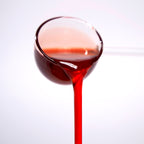 Close-up of grapefruit concentrated syrup pouring, featuring a vibrant reddish-pink color and zesty citrus texture.