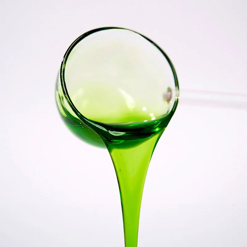 Close-up of green apple concentrated syrup pouring, showcasing a vibrant clear green color and zesty fruity texture.