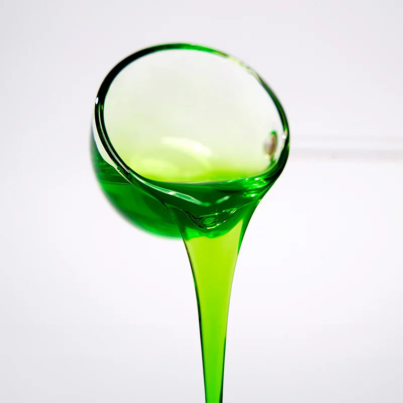 Close-up of honeydew concentrated syrup pouring, showcasing a vibrant clear green color and rich, sweet melon texture.