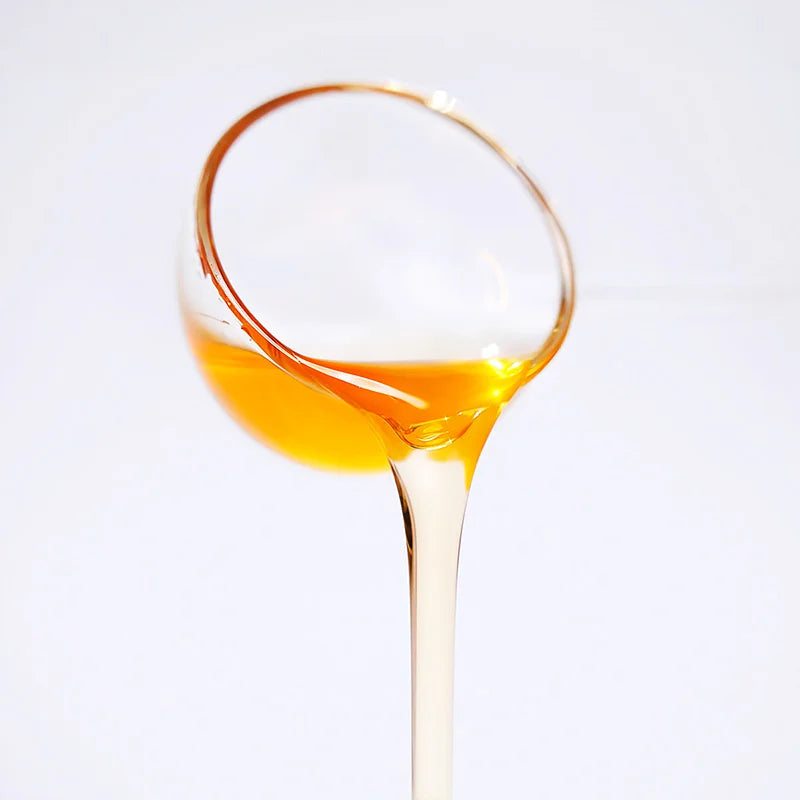 Close-up of lychee concentrated syrup pouring, showcasing a clear amber glow and enticing tropical fruity texture.