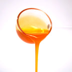 Close-up of mango concentrated syrup pouring, featuring a bright orange color and rich fruity texture.