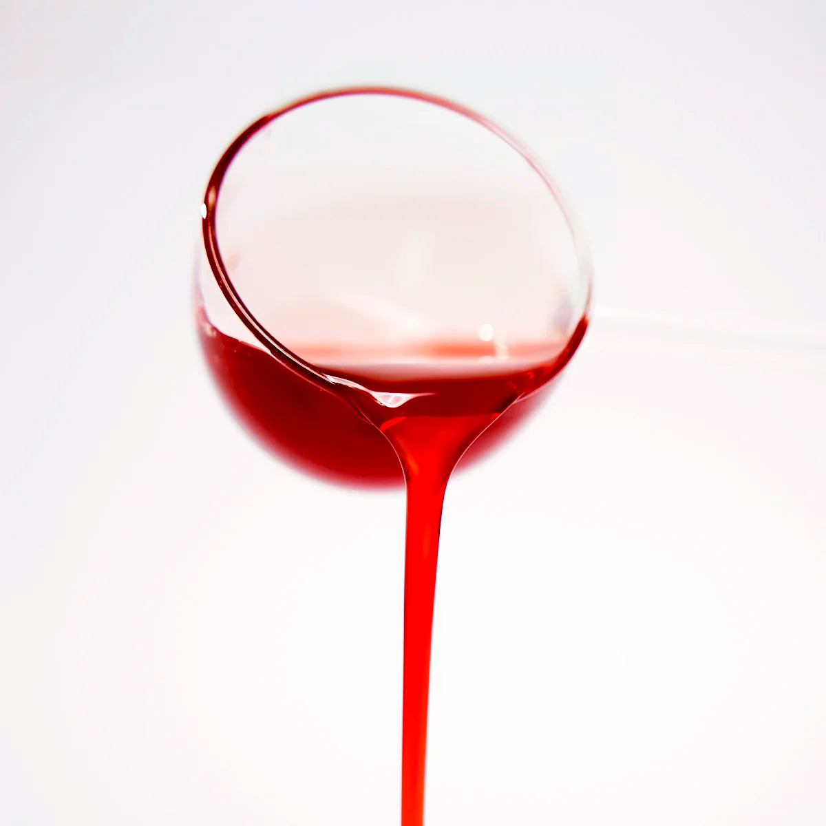 Close-up of rose syrup being poured, showcasing its ruby-red color and rich consistency.
