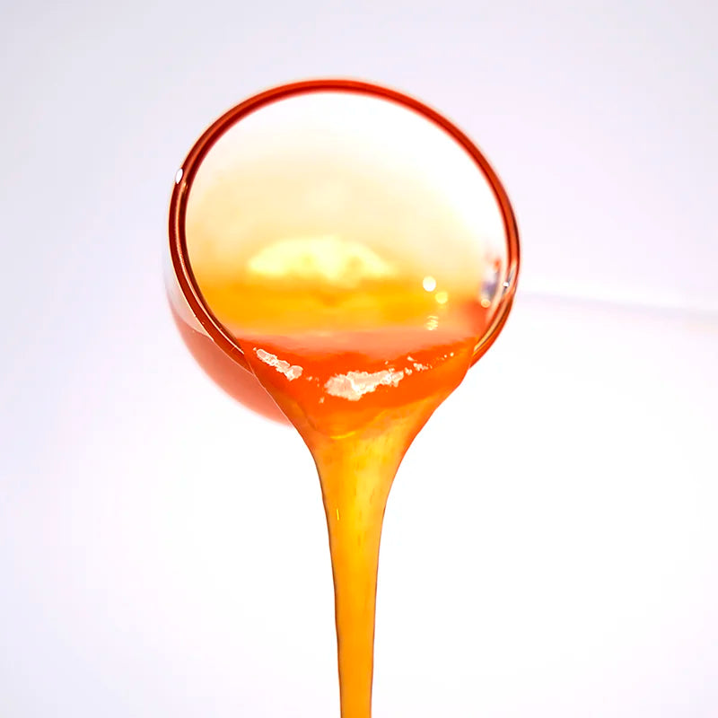 Close-up of passion fruit concentrated syrup pouring, featuring a seedless golden texture and smooth, rich fruity aroma.