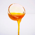 Close-up of orange concentrated syrup texture being poured, showing vibrant color and consistency.